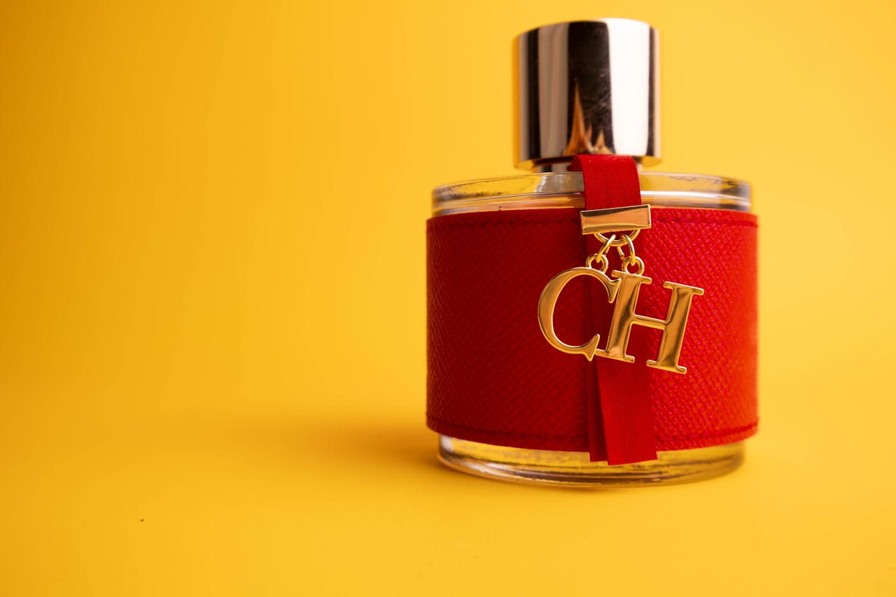 Luxury perfume bottle with red accent on a vibrant yellow background, showcasing elegance and style.