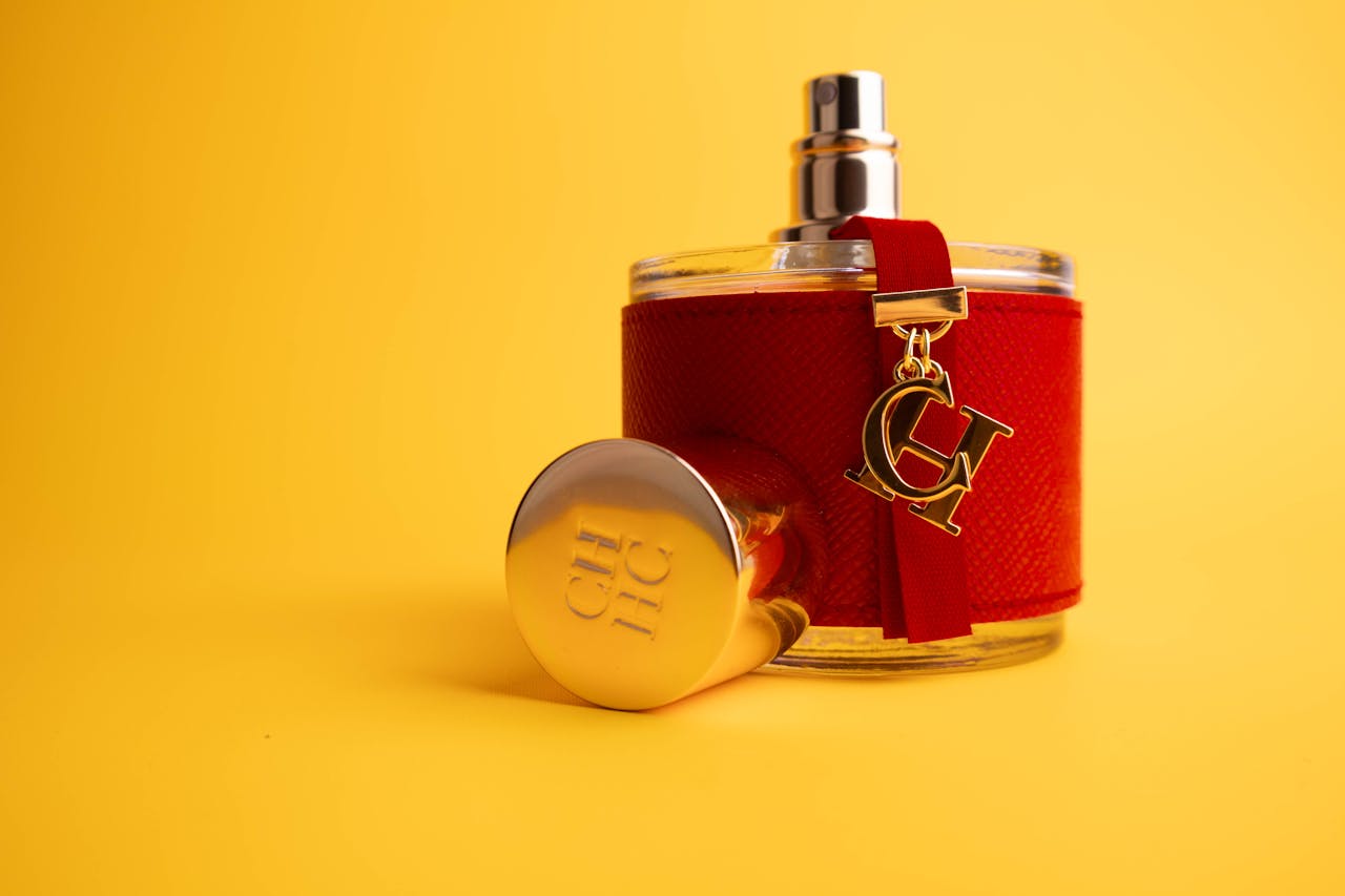 Stylish red perfume bottle with gold detailing on a bright yellow backdrop, ideal for luxury advertising.