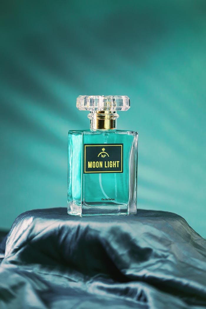 Artistic shot of Moon Light perfume bottle set against a soft blue backdrop. Perfect for luxury branding.